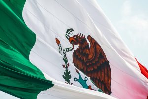 Mexican flag against a sky, blowing lightly in the wind.